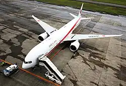 Aircraft on the ground, with airstairs docked to the front left door.