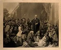 Engraving of Wesley standing on a plinth and preaching to a crowd.