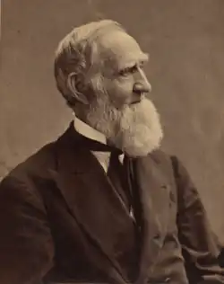 An old man in profile, facing to the left. He has a very bushy beard.