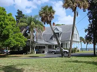 A house with palm trees nearby and a pickup truck in front.
