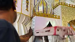 Man touching a Tadjah in progress for Hosay