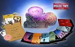 Home media packaging in the shape of an orb with a purple center, surrounded by its contents including disc cases and collectibles