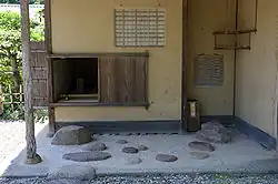 Small entranceway to a traditional tea house, with weathered wood and earthen walls