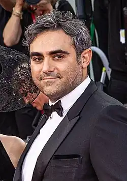 A man in a black tuxedo glancing towards a camera