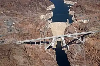The bridge is silhouetted against the sky with the Colorado river far below