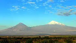 not very sharp snow-capped mountain peak in the distance, under a blue sky with a few small clouds