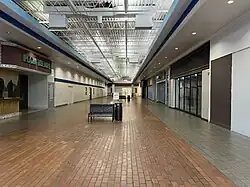 A mostly deserted corridor of a shopping mall, facing Warehouse Bargains