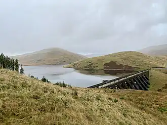 A dam head and spillway with trees on the far side