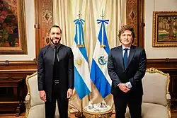Nayib Bukele and Javier Milei standing in front of the flags of El Salvador and Argentina