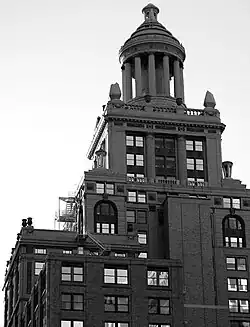A high rise building with many tiers and a ten-columned cupola topping it.