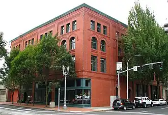 Photograph of a four-story, brick building on an urban street corner.