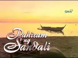 An image of a beach sand, with a boat over a body of water and an orange sky. The series title is displayed on the lower left side of the image. The logo of GMA Network is displayed on the upper right side of the image.