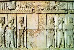 Stone-carved wall depicting Persians and Medes of the Achaemenid army under the Faravahar at the Apadana Hall in the city of Persepolis