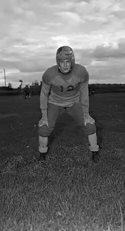 Black and white image of Peter Lougheed dressed in football equipment.