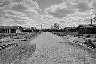 An empty road with abandoned housing units on either side.