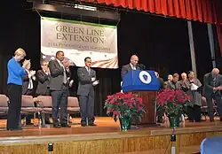 Politicians on an indoor stage at a press conference