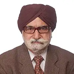 Portrait of Harkishan Singh wearing a turban, glasses, and a suit with a patterned tie.