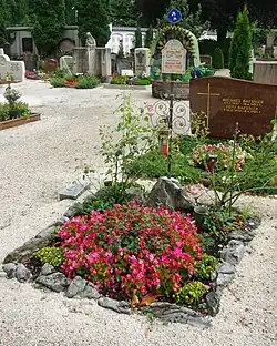 A color photograph of a grave with flowers blooming on its surface