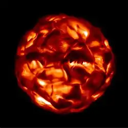 A spherical object, dimly red-to-black with highly complex and chaotic, randomly-oriented patterns of varying brightness on its surface, against a black background