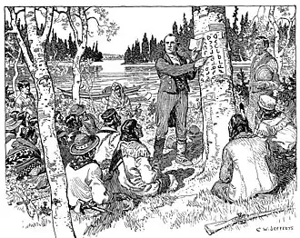 A white man stands in front of a gathering of Cree people, teaching his writing system to them.