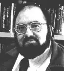 Black and white head shot of a bearded man wearing glasses