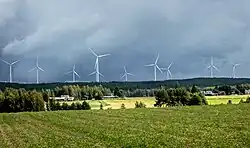 Photograph of Santavuori on a cloudy day. A wind farm sits on the hill.