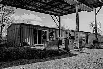 An abandoned store building with old gas pumps out front.