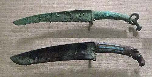 Shang dynasty curved bronze knives with turquoise inlays and animal pommel. 12th–11th centuries&nbsp;BC. Such knives may be the result of contacts with northern people.[87]