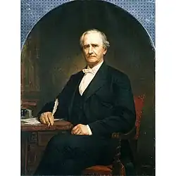 Elderly man in 19th century formal dress seated and holding a quill