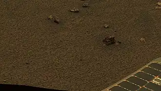 Figure 7. Many hematite spherules over an area bigger than 1 m2. This image is cropped from the foreground of Figure 9. At full size, it is good at clearly imaging many thousands of hematite spherules (about 20,000 spherules strewn over an area of roughly 2 m2). The clarity of the imaging was due to the favorable lighting and dust conditions. The larger blocks in the image are crater ejecta from the adjacent tiny Granada Crater (refer to the right side of Figure 9 below). These crater ejecta are small pieces of Meridiani sediment. Hematite spherules embedded in the ejecta sediment are visible. Some of Opportunitys solar panels are visible in the foreground. Image taken on Sol 1162 (2007-05-01).