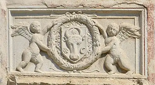 Relief with the coat of arms of Moldavia in a laurel wreath hold by two cherubs (aka putti), above the pisanie of the Saint Demetrius of Thessaloniki Church, Suceava, unknown sculptor, 1534[11]
