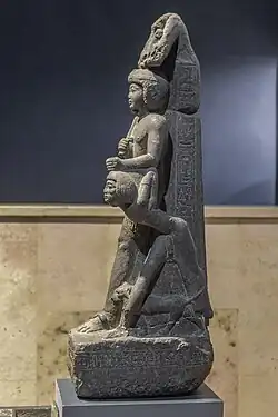 Standing man holding the hair of a man on his knees.