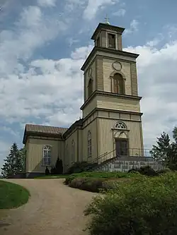 A church building atop a hill with a clear, cloudy sky in the background.