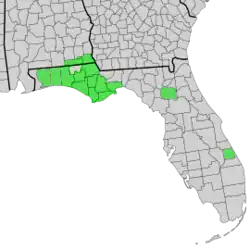 Map of Alabama and Florida with counties of distribution of Symphyotrichum chapmanii shaded in green: Alabama counties — Geneva and Houston; Florida counties — Alachua, Bay, Calhoun, Franklin, Gulf, Jackson, Liberty, Okaloosa, Santa Rosa, St. Lucie, Wakulla, Walton, and Washington