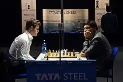 Carlsen thinks on a move, while Anand looks away