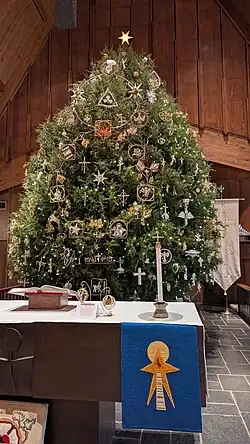 The 68th Annual Chrismon Tree at Ascension Lutheran Church in Danville, Virginia. In the center of the tree sits a 9-foot-tall Chrismon, titled "The Christian Year Series". It depicts the Holy Trinity and the Church's liturgical calendar. Blue paraments on the altar signify the season of Advent.