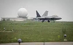 A F-22A Raptor taxis at Mihail Kogalniceanu, with a radar station radome in the background.
