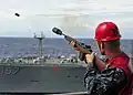 A United States Navy sailor using a line thrower