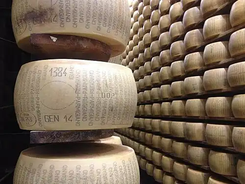 A wheel of Parmigiano Reggiano with PDO marking and "Parmigiano Reggiano" written around the side. An official certification will be stamped into the central oval when it is graded.