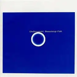 A blue rectangle on a white background. In the rectangle is a white circle, above it, in grey, "Underworld, Beaucoup Fish" is written.