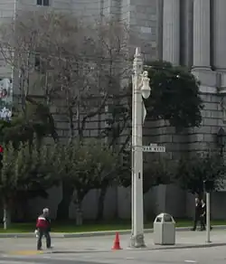 A square utility pole with an ornamental streetlight