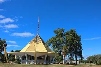 A round, bandstand-like structure with a pointed golden roof and a radio antenna that bears the word "WISCONSIN" in red letters placed along its length.