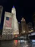 Wrigley Building lit up at night with the American flag from the Chicago River in July 2024