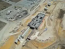 Drone shot of a sandy construction site with concrete retaining walls and bridges