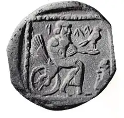 A coin showing a bearded figure seating on a winged wheel, holding a bird on an outstretched hand.