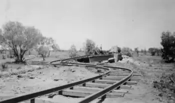 Track severely twisted in the foreground leading to a bridge that has been washed down the river a significant distance