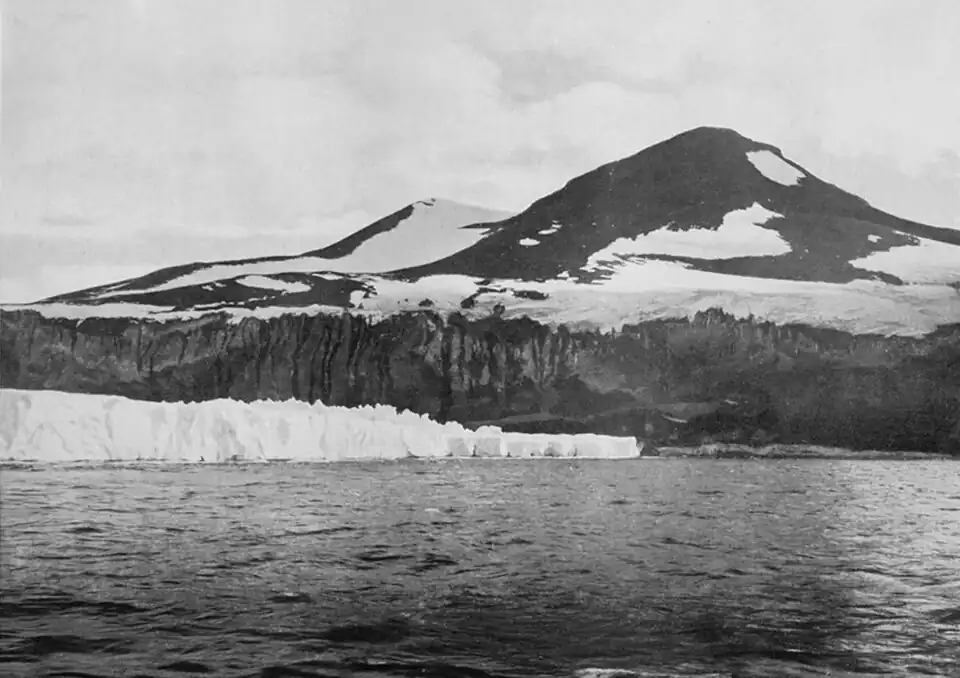 Photo of a cliff below a double peak, with a glacier edge extending from the left