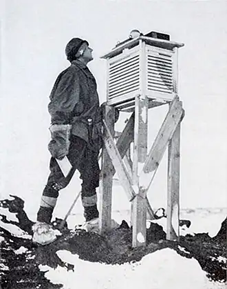 Photo of a man peering at a slatted box propped up at eye level by a makeshift wooden base