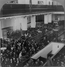 Black and white photograph of a recent immigrants queuing in the Immigrant Building on Ellis Island, New York Harbor.