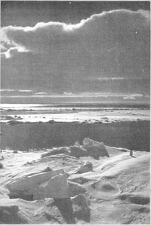 Sharply lit photo of sea ice with jagged protrusions, open leads, and a sky dominated by a large cloud